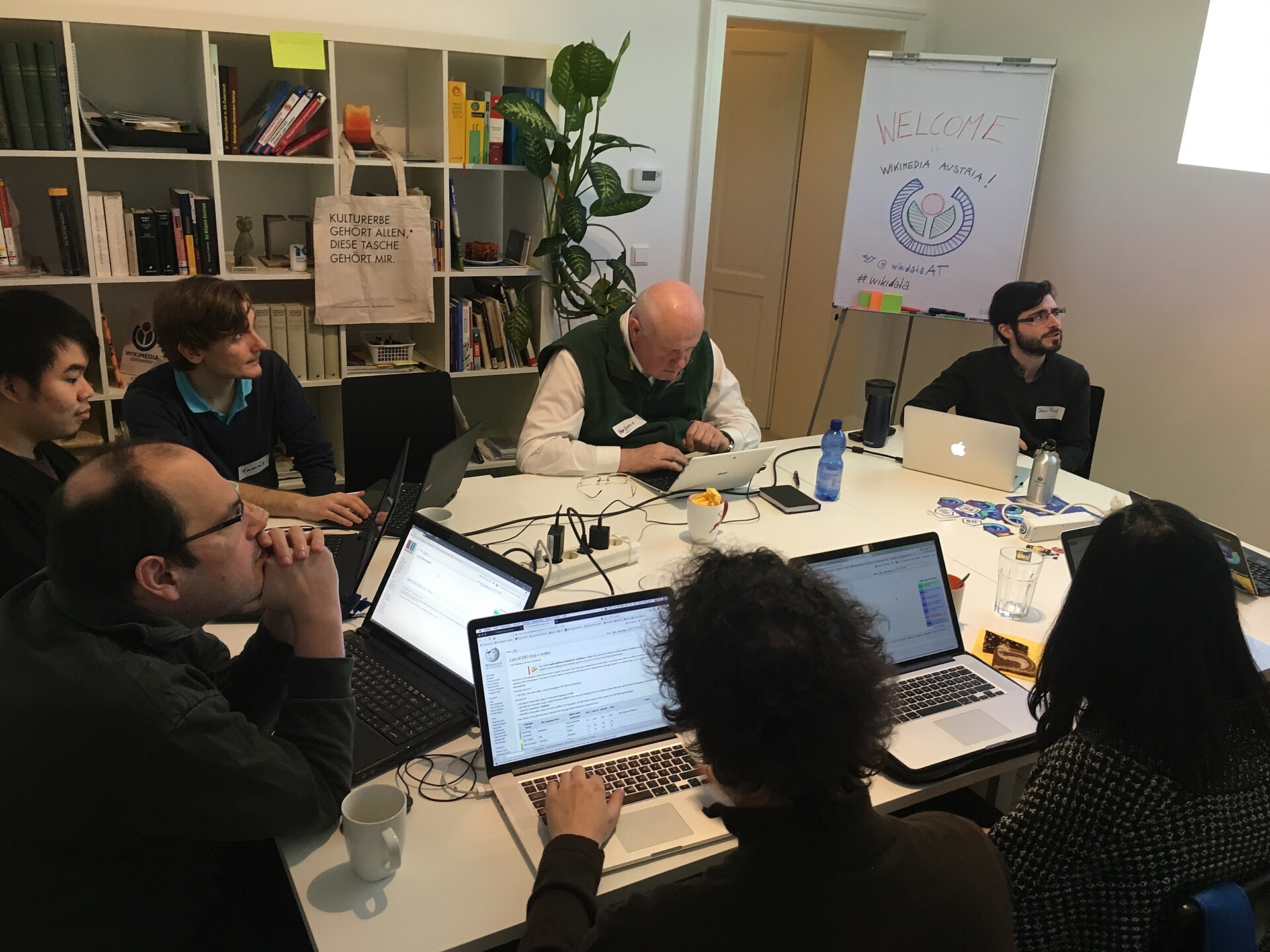 A professional team reviews data and workflow details together on laptop computers.