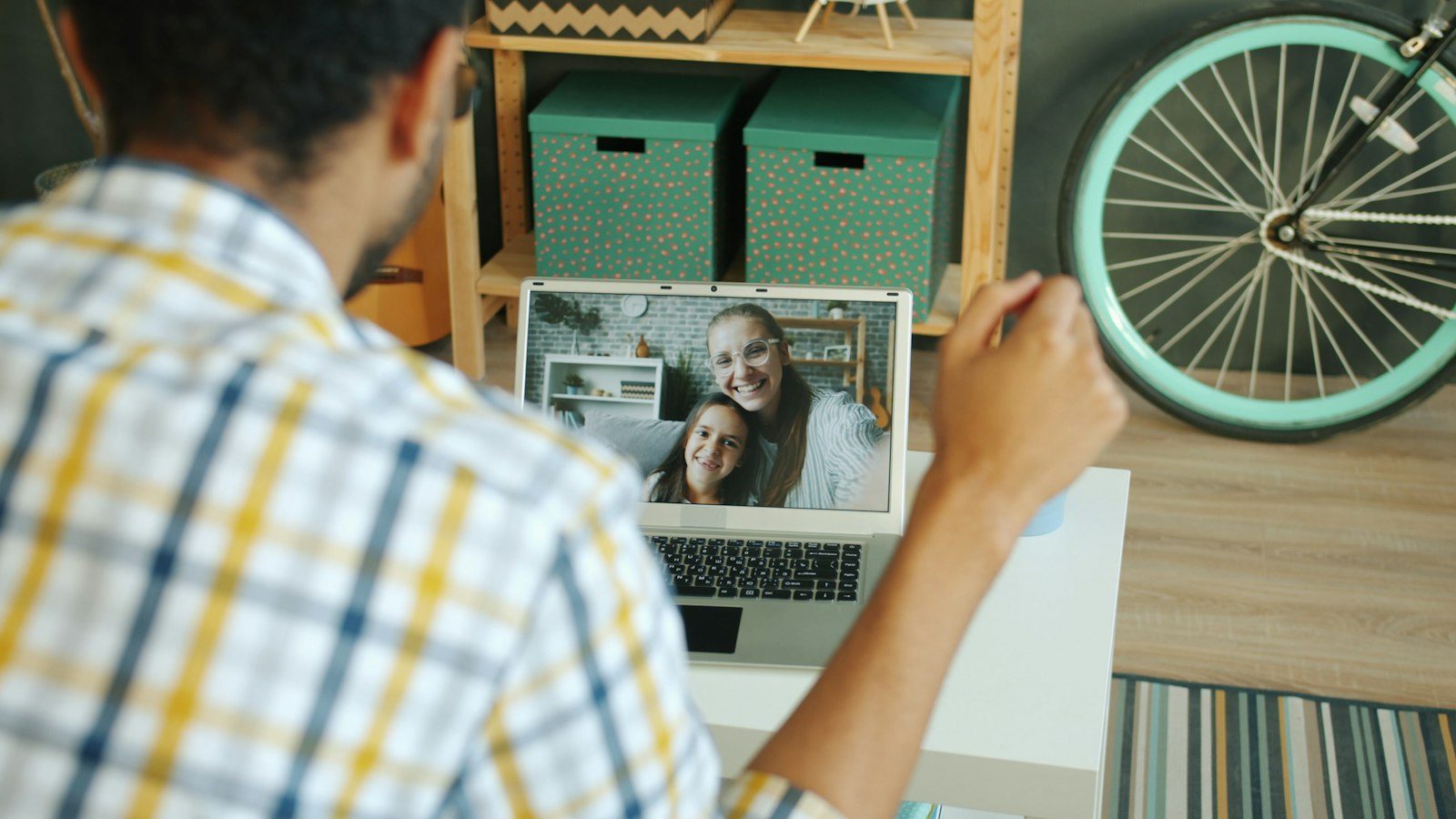 An office floor with scattered empty desks and an active video conference displayed on a monitor.
