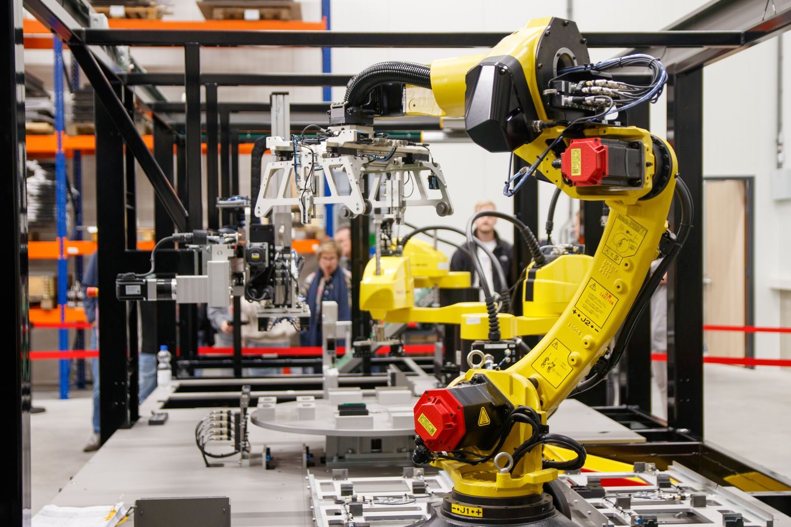 Robotic arms weld components on a modern factory assembly line, generating sparks.
